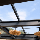 Pergola moderne avec toit en verre trempé transparent et lampes suspendues créant une ambiance chaleureuse en plein air