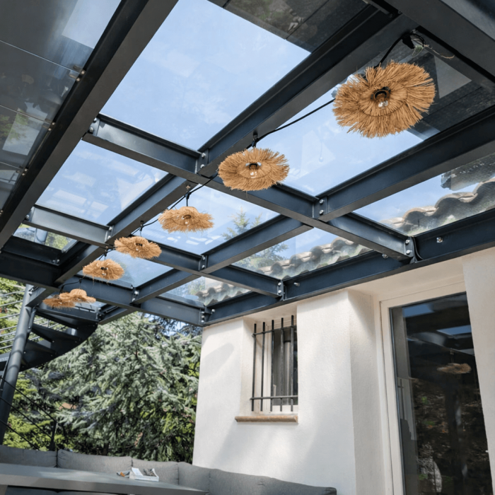 Pergola moderne avec toit en verre trempé transparent et éclairage suspendu créant une atmosphère extérieure élégante