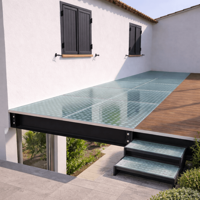 Terrasse en verre avec motif circulaire et escalier en métal, offrant une transition élégante vers un espace extérieur ouvert. Un design moderne et pratique pour une zone de détente en plein air.