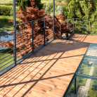 Terrasse en verre trempé avec balustrade métallique et vue sur un jardin verdoyant