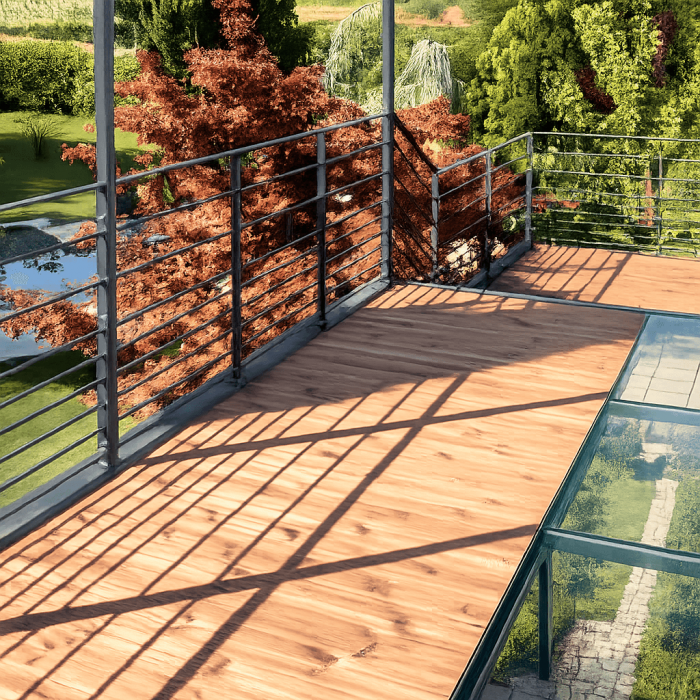 Terrasse en verre trempé avec balustrade métallique et vue sur un jardin verdoyant