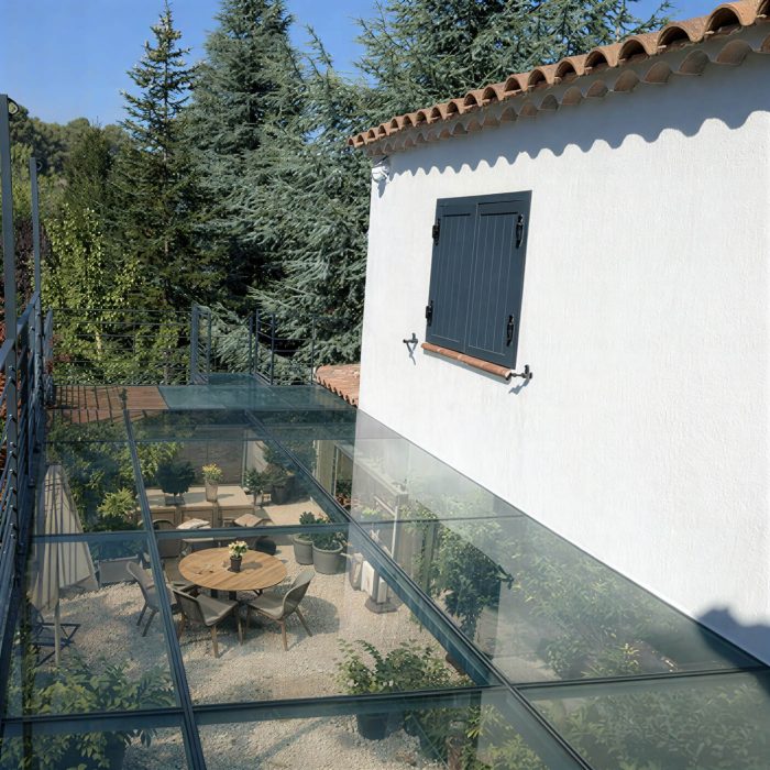 Vue aérienne d'une terrasse en verre trempé avec mobilier extérieur sur un jardin verdoyant