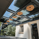Véranda avec toit en verre trempé, éclairage doux et décoration moderne pour une ambiance extérieure lumineuse