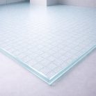 Plancher en verre trempé transparent de 27 mm avec texture industrielle, apportant une touche urbaine et graphique aux éléments décoratifs intérieurs.