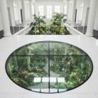 Plancher en verre trempé circulaire pour intérieur de jardin avec vue sur la nature, plantes et chemin de pierre