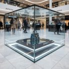 Vitrine en verre transparent exposant un sac de luxe Aurum avec éclairage LED dans un centre commercial moderne